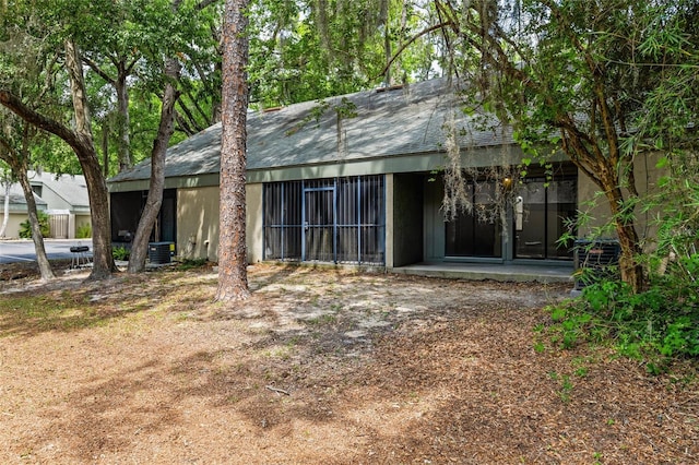 back of property featuring central AC unit and roof with shingles