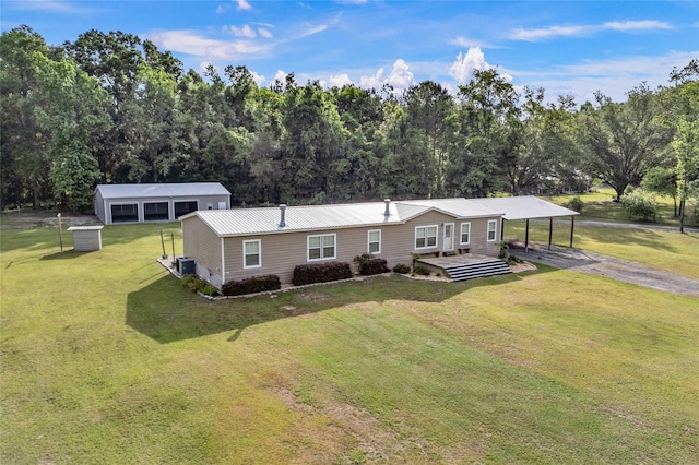 single story home with a carport, a pole building, an outbuilding, a front yard, and driveway