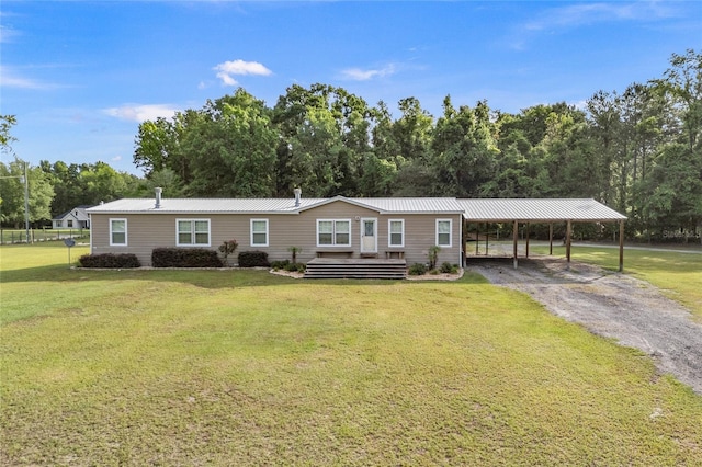 manufactured / mobile home with a front yard, metal roof, driveway, and view of wooded area