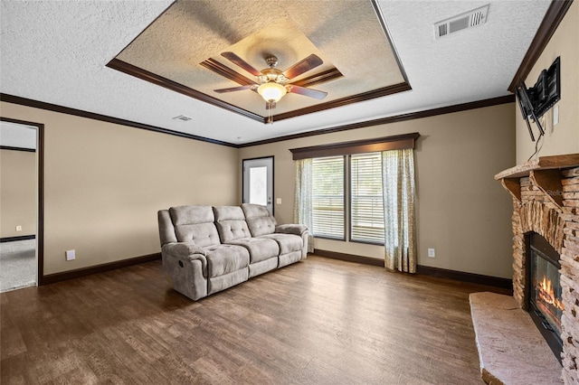 living area with a textured ceiling, dark wood-style flooring, a fireplace, a ceiling fan, and baseboards
