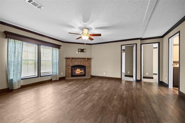 unfurnished living room with dark wood finished floors, ceiling fan, crown molding, a fireplace, and a textured ceiling