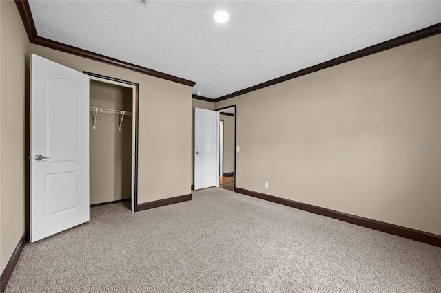 unfurnished bedroom featuring light carpet, crown molding, baseboards, a closet, and a textured ceiling
