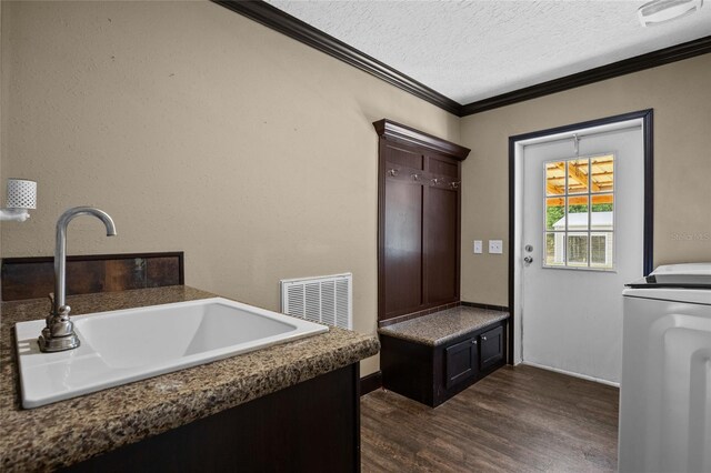 laundry area with ornamental molding, a textured ceiling, dark wood-type flooring, washer / dryer, and baseboards