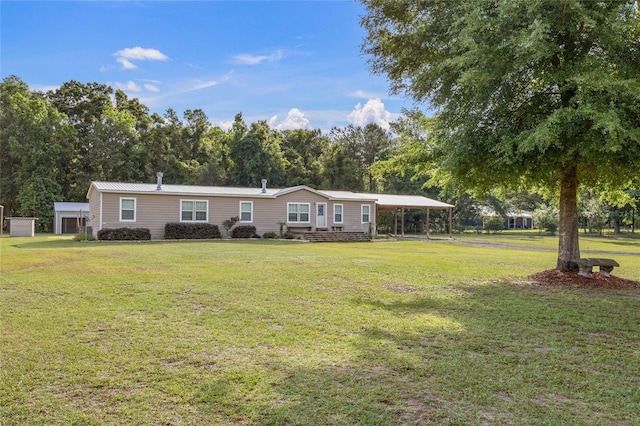 manufactured / mobile home featuring a carport, a front lawn, and view of scattered trees