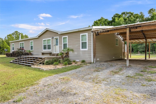 manufactured / mobile home featuring a carport, dirt driveway, metal roof, and a front yard
