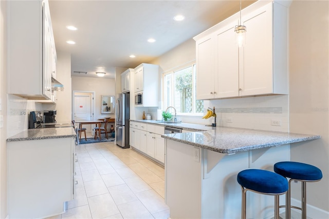 3242 NW 23rd Rd, Gainesville, FL 32605 - kitchen featuring stainless steel appliances, a sink, a kitchen bar, a peninsula, and backsplash