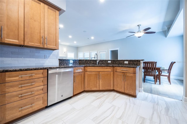 13209 SW 3rd Ln, Newberry, FL 32669 - kitchen with stainless steel dishwasher, a ceiling fan, a sink, brown cabinetry, and dark stone countertops