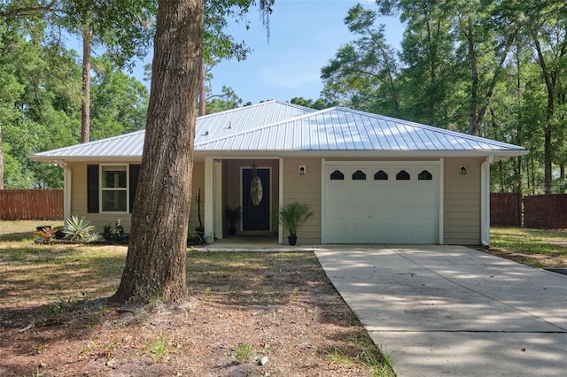 ranch-style house featuring fence, driveway, a garage, and metal roof