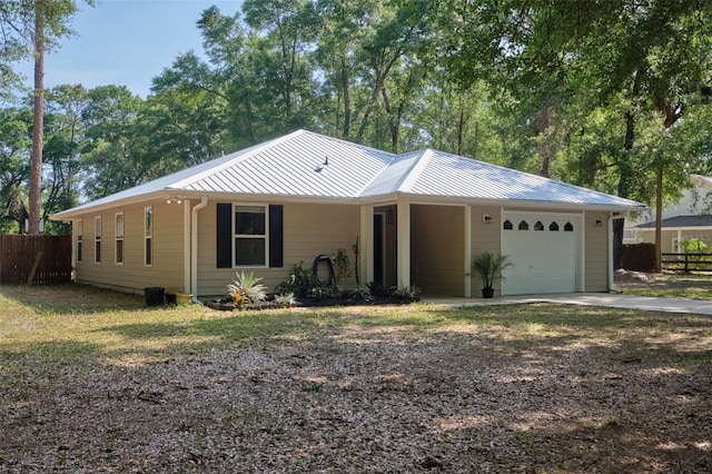 view of front of property featuring fence, an attached garage, driveway, and metal roof