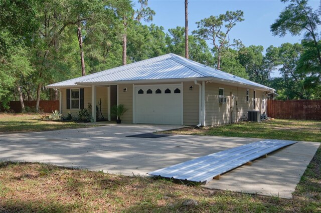 single story home featuring fence, a garage, central AC, and metal roof