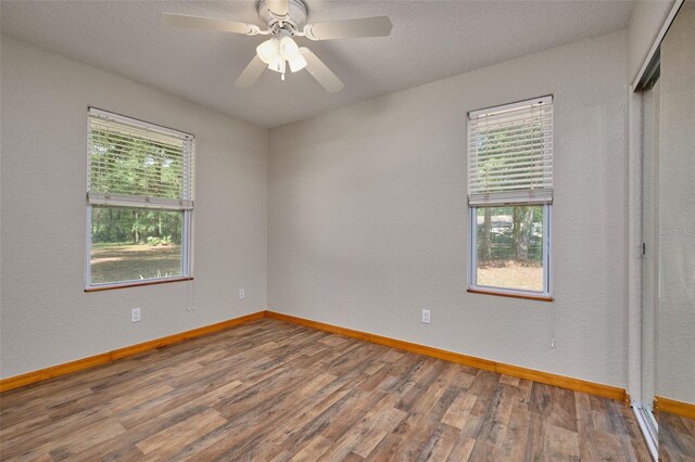 spare room featuring wood finished floors, baseboards, a textured ceiling, and ceiling fan