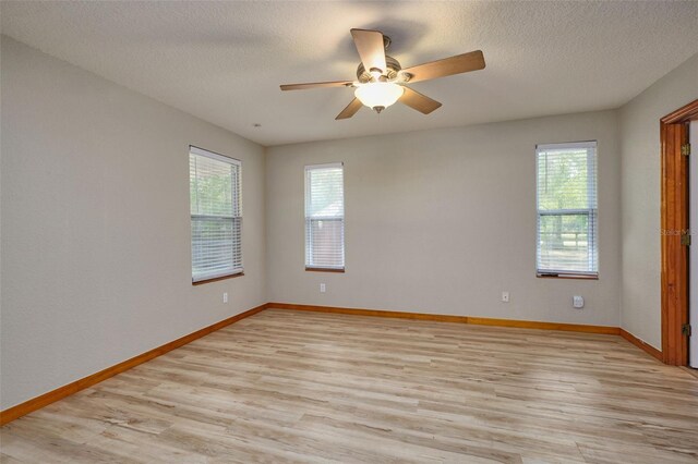 unfurnished room with healthy amount of natural light, light wood-style floors, ceiling fan, baseboards, and a textured ceiling