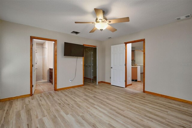 unfurnished bedroom with light wood-type flooring, baseboards, a spacious closet, and a closet