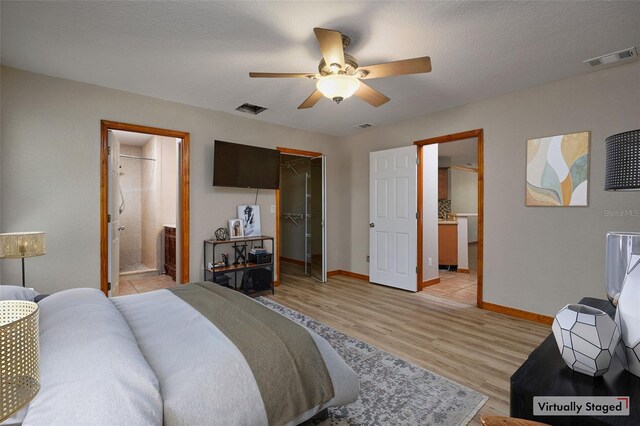 bedroom with a walk in closet, baseboards, light wood-style flooring, and ensuite bathroom