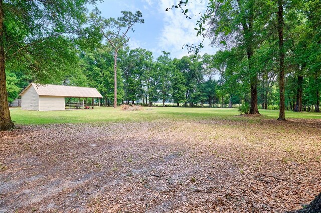 view of green lawn with an outbuilding, an outdoor structure, and a detached carport