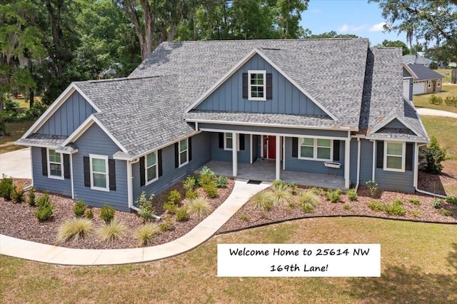 view of front of home featuring board and batten siding, covered porch, a shingled roof, and a front lawn