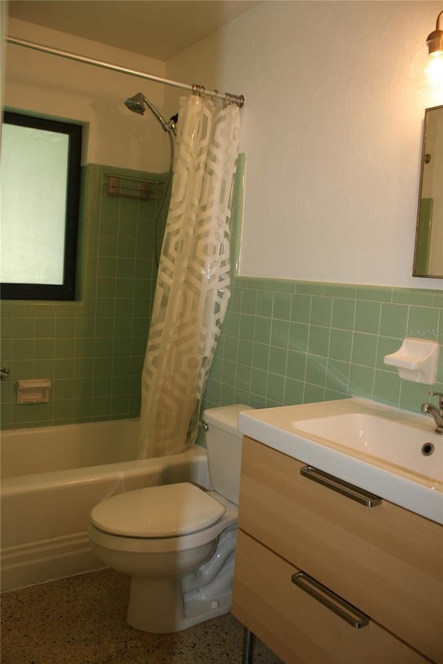 1226 NE 17th Ave, Gainesville, FL 32609 - bathroom with shower / bathtub combination with curtain, vanity, wainscoting, tile walls, and speckle patterned floor