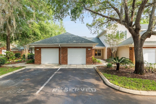 view of front facade with brick siding, a shingled roof, an attached garage, and driveway