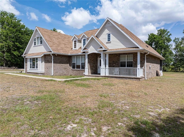 view of front of house featuring brick siding, a porch, and a front lawn