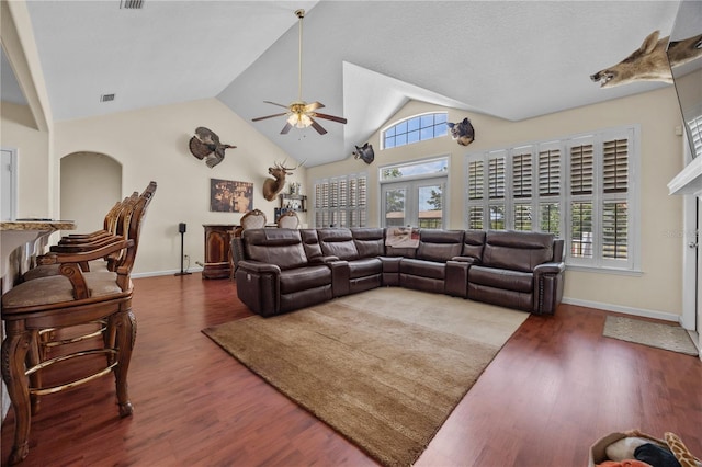 living room with a ceiling fan, vaulted ceiling, plenty of natural light, and baseboards