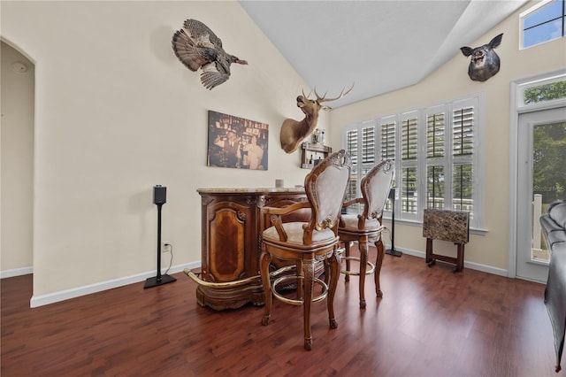 sitting room with plenty of natural light, wood finished floors, a dry bar, baseboards, and vaulted ceiling