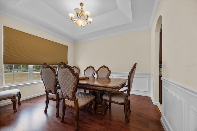 dining area featuring a chandelier, dark wood-style floors, arched walkways, a wainscoted wall, and a raised ceiling