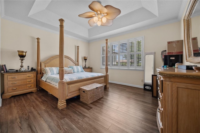 bedroom with a tray ceiling, baseboards, dark wood-type flooring, ceiling fan, and ornamental molding