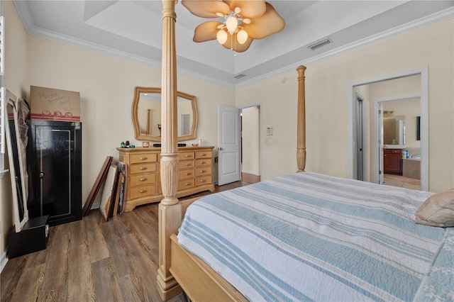 bedroom featuring wood finished floors, crown molding, a raised ceiling, connected bathroom, and a ceiling fan