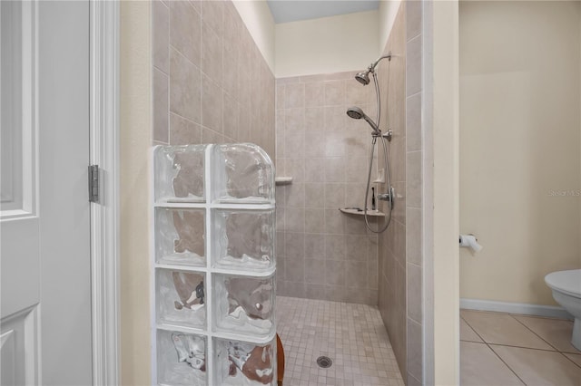 bathroom with a tile shower, tile patterned flooring, and toilet