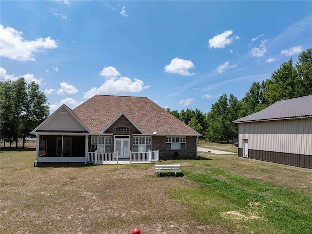 rear view of house with a sunroom, a lawn, french doors, and a shingled roof