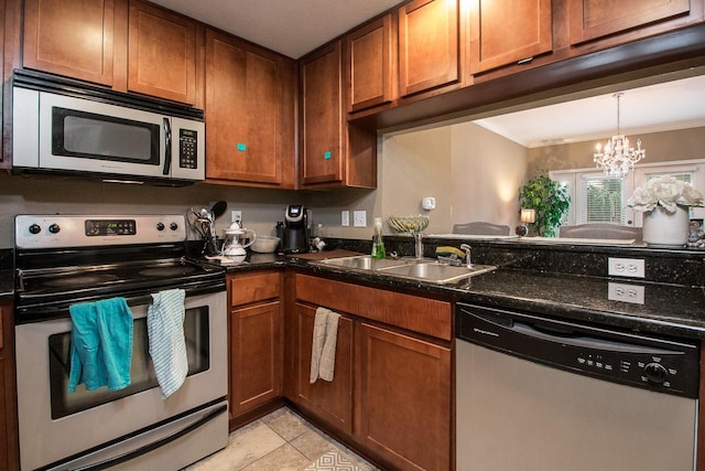 kitchen featuring stainless steel appliances, a sink, ornamental molding, a chandelier, and brown cabinets