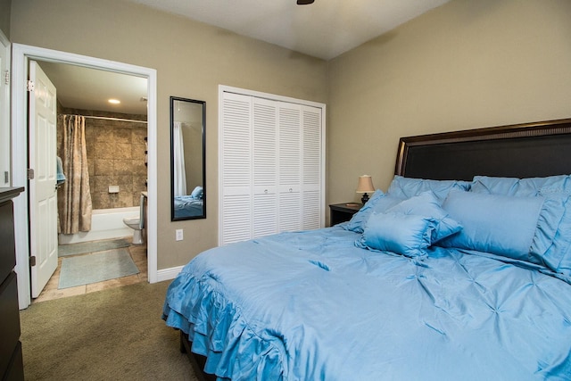 carpeted bedroom featuring a closet, ensuite bath, baseboards, and ceiling fan