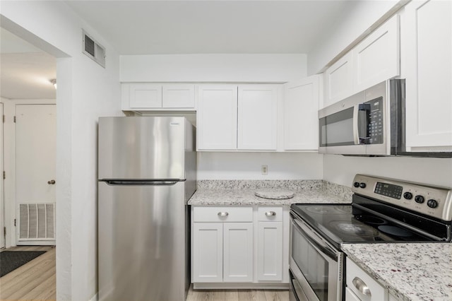 kitchen featuring appliances with stainless steel finishes, light wood-type flooring, white cabinets, and light stone countertops