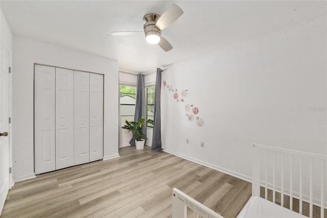 unfurnished bedroom with light wood-style floors, a closet, ceiling fan, and baseboards