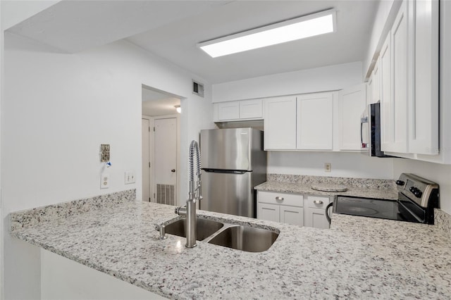 kitchen with stainless steel appliances, white cabinetry, light stone counters, and a sink