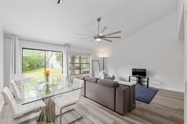 living area with vaulted ceiling, a ceiling fan, and light wood finished floors