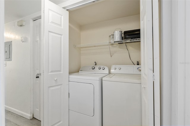 clothes washing area featuring washer and clothes dryer, light wood-style floors, and baseboards