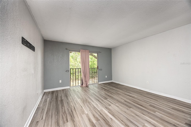 507 NW 39th Rd Unit 235, Gainesville, FL 32607 - unfurnished room featuring wood finished floors, baseboards, a textured ceiling, and a textured wall
