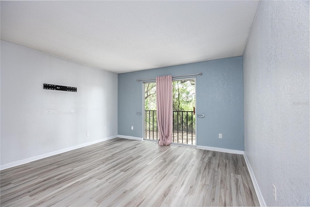 507 NW 39th Rd Unit 235, Gainesville, FL 32607 - empty room featuring light wood-style flooring, baseboards, a textured wall, and a textured ceiling