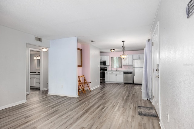 507 NW 39th Rd Unit 235, Gainesville, FL 32607 - unfurnished living room with light wood finished floors, baseboards, and a sink