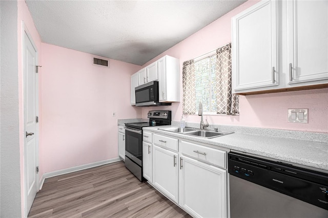 507 NW 39th Rd Unit 235, Gainesville, FL 32607 - kitchen with appliances with stainless steel finishes, a sink, white cabinets, light wood-type flooring, and light countertops