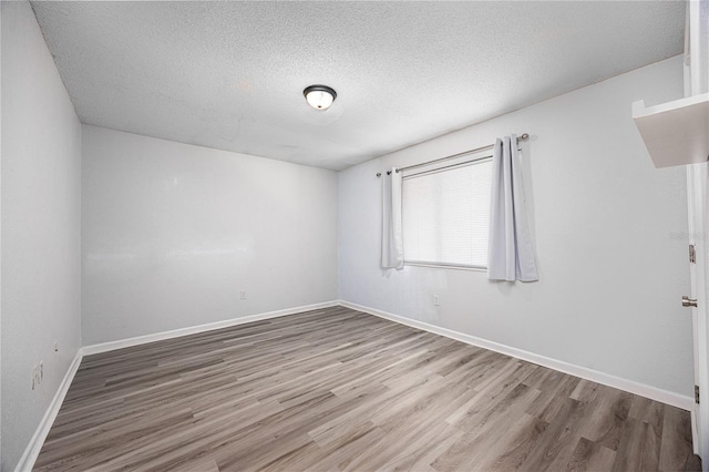 507 NW 39th Rd Unit 235, Gainesville, FL 32607 - spare room featuring wood finished floors, a textured ceiling, and baseboards