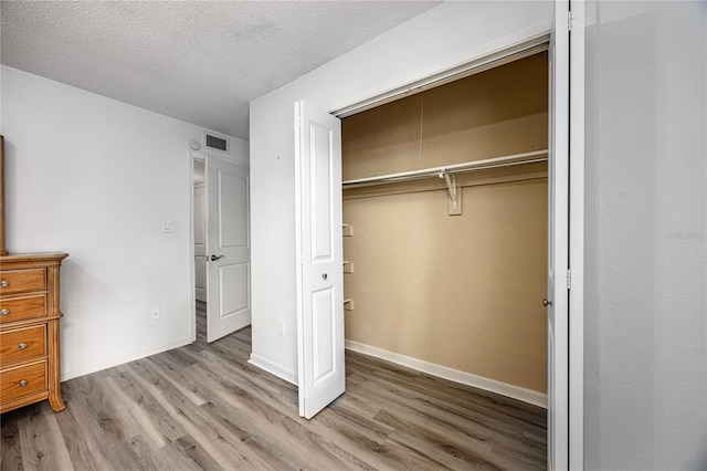 507 NW 39th Rd Unit 235, Gainesville, FL 32607 - unfurnished bedroom with wood finished floors, a closet, a textured ceiling, and baseboards