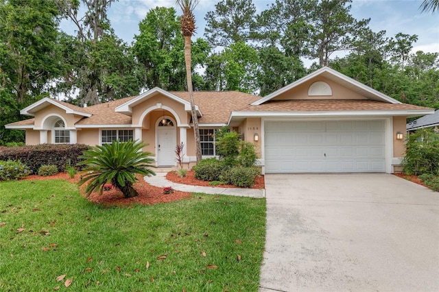 ranch-style home featuring stucco siding, driveway, a front yard, a garage, and a shingled roof