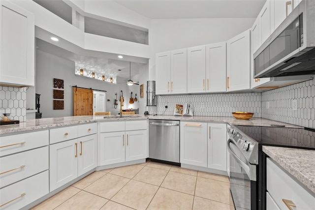 kitchen with stainless steel appliances, white cabinetry, light tile patterned floors, backsplash, and high vaulted ceiling