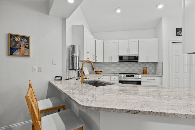 kitchen with a sink, appliances with stainless steel finishes, backsplash, light stone counters, and recessed lighting