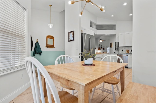 dining room featuring light tile patterned floors, a towering ceiling, and ceiling fan