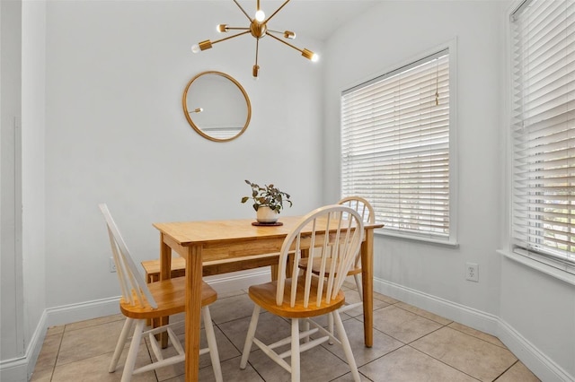 dining area with a chandelier, light tile patterned flooring, and baseboards