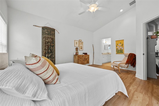 bedroom featuring light wood-style floors, ensuite bathroom, ceiling fan, high vaulted ceiling, and baseboards