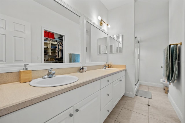bathroom featuring tile patterned floors, double vanity, a shower stall, baseboards, and a spacious closet